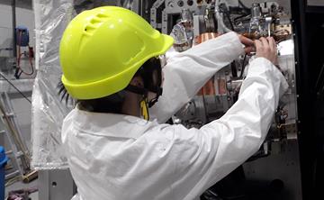 An apprentice in hard hat and lab coat working in the lab at UK ATC.